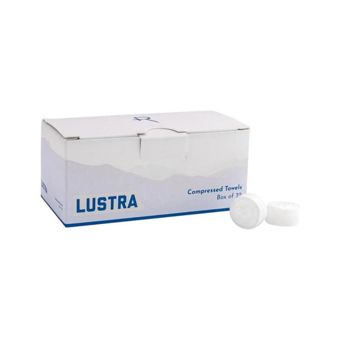 Une boîte blanche étiquetée « Recovery Lustra Compressed Towels – 32 unités », avec deux petites serviettes compressées rondes placées à côté sur fond blanc.